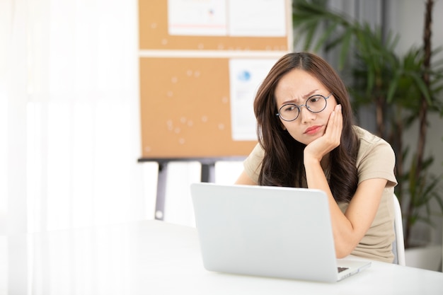 Zaken Aziatische vrouw Droevig en ongerust werkend met laptop in een bureau