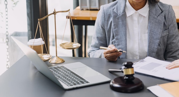 Zaken en advocaten bespreken contractpapieren met koperen schaal op bureau in kantoor Wet juridische diensten advies rechtvaardigheid en wet concept foto met filmkorreleffect
