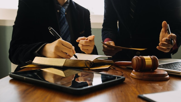 Zaken en advocaten bespreken contractpapieren met koperen schaal op bureau in kantoor Wet juridische diensten advies rechtvaardigheid en wet concept foto met filmkorreleffect