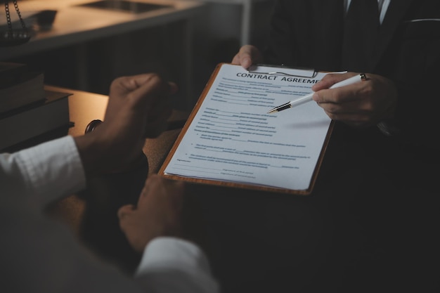 Zaken en advocaten bespreken contractpapieren met koperen schaal op bureau in kantoor Wet juridische diensten advies rechtvaardigheid en wet concept foto met filmkorreleffect