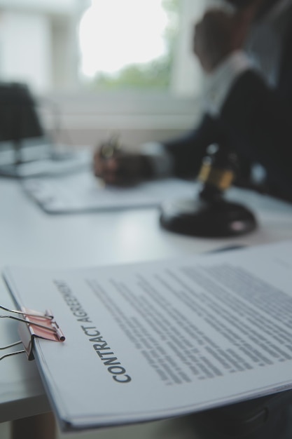 Zaken en advocaten bespreken contractpapieren met koperen schaal op bureau in kantoor Wet juridische diensten advies rechtvaardigheid en wet concept foto met filmkorreleffect