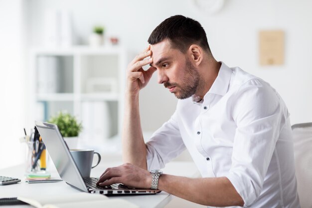 zaken, mensen, deadline en technologie concept - gestrest zakenman met laptop computer op kantoor