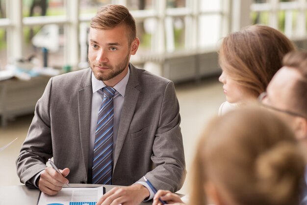 zaken, mensen en statistiekenconcept - commercieel team met grafiek op klembordvergadering op kantoor