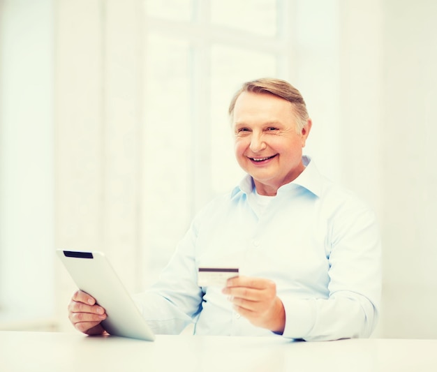 zaken, oudheid, online bankieren, internetwinkelen en oudheidsconcept - glimlachende oude man met tablet-pc en creditcard thuis