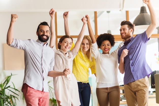 zaken, triomf, gebaar, mensen en teamwerkconcept - gelukkig internationaal creatief team dat de handen omhoog steekt en de overwinning in functie viert