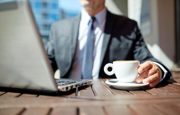 zaken, warme dranken, pauze en mensen en concept - senior zakenman met laptop buiten koffie drinken uit een espressokopje