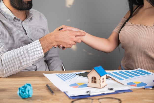 Zakenlieden bespreken schema's en huis. handenschudden