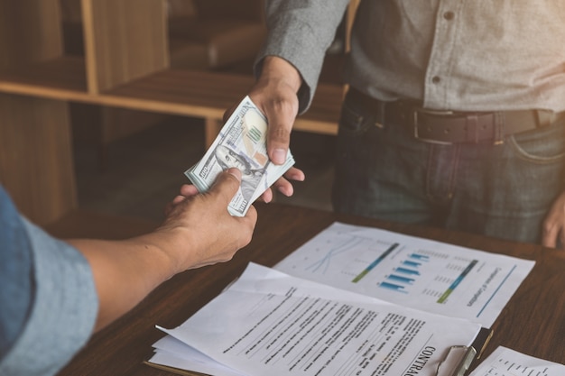 Foto zakenlieden die handdruk met geld in handen maken, corruptie en omkoperijconcepten.