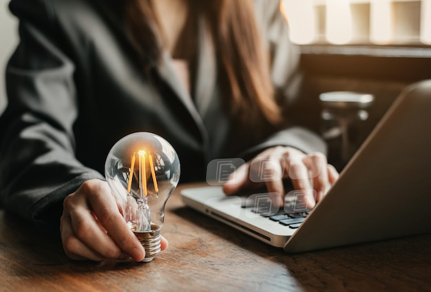 Zakenlieden dragen gloeilampen met het idee geld te besparen door 's ochtends op het werk met laptops en tabbladen te werken