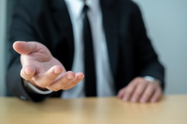 Zakenlieden dragen pakken zittend aan een bureau en begroeten sommige mensen met de hand