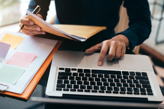 Zakenman aan het werk op kantoor met documenten en laptop op zijn bureau financieel adviseur die gegevens analyseert