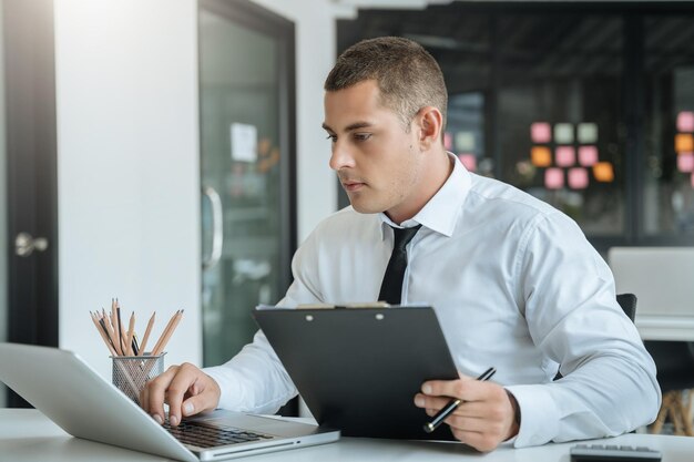 Zakenman aan het werk op kantoor met laptop en documenten op zijn bureau financieel adviseur die gegevens analyseert