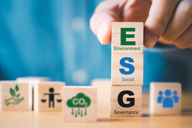 Zakenman assembleert ESG-formulering op houten kubusblok voor duurzame organisatieontwikkeling en corporatie van het concept Milieu Sociaal Bestuur