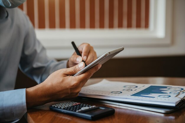 Zakenman berekenen en analyseren grafiekdocument financieel met tablet en laptop op kantoor