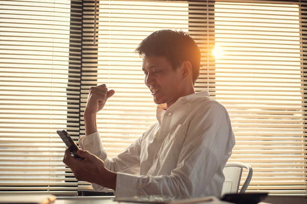 Foto zakenman blij nadat hij goed nieuws heeft ontvangen om een nieuwe baan van smartphone te krijgen