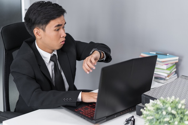 zakenman controleren tijd op wacht terwijl het gebruiken van laptop