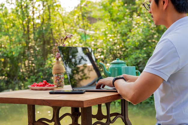 Zakenman die aan laptop met theekop en fruit op lijst werkt