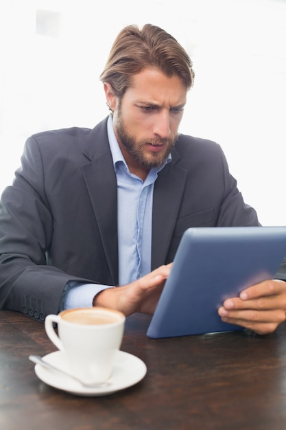 Zakenman die aan zijn tablet werkt die koffie heeft