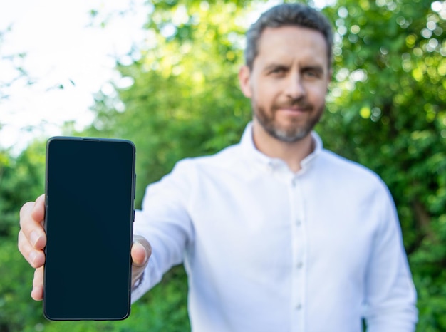 Zakenman die app op telefoon toont met selectieve aandacht foto van zakenman die app met kopieerruimte toont zakenman die app toont zakenman die app buiten toont