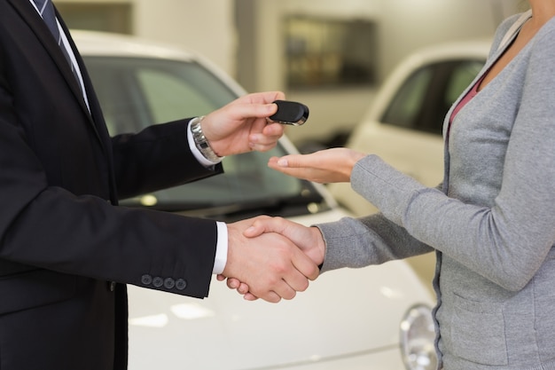 Zakenman die autosleutel geeft terwijl het schudden van een klantenhand