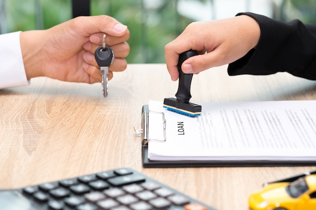 Zakenman die autosleutel geeft terwijl leningsovereenkomst die wordt goedgekeurd