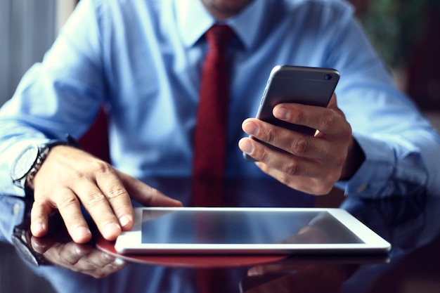 Zakenman die een digitale tabletcomputer gebruikt met een moderne mobiele telefoon Nieuwe technologieën voor een succesvol workflowconcept