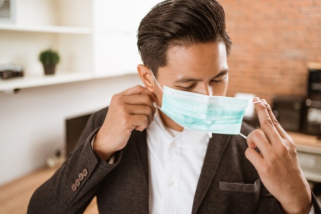 Zakenman die een gezichtsmasker draagt terwijl hij in zijn kantoor werkt