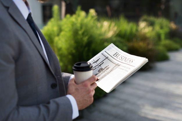 Zakenman die een kop van koffie houdt en een krant leest