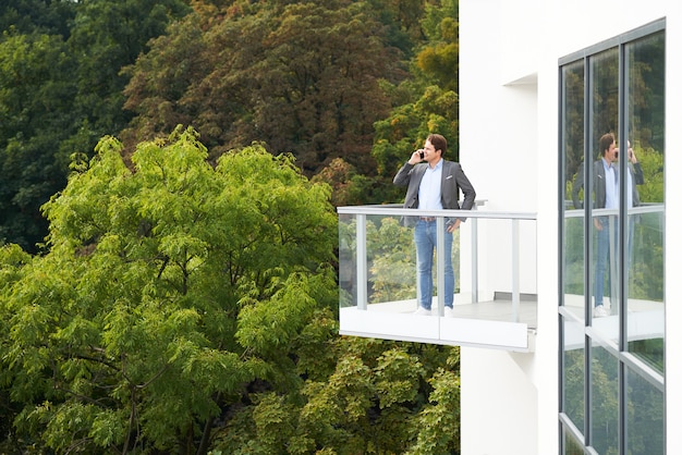 zakenman die een masker draagt dat op het balkon staat tegen de natuur