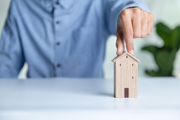 Zakenman die een mini houten huismodel kiest van een model op een houten tafel