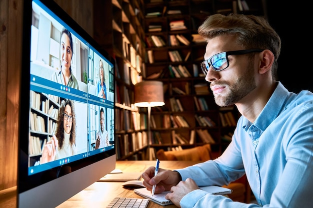 Zakenman die een virtuele teamvergadering heeft via een videoconferentie met behulp van een computer werknemer op sociale afstand die vanuit zijn kantoor werkt en met verschillende collega's in een externe videoconferentieconferentie online chatteert