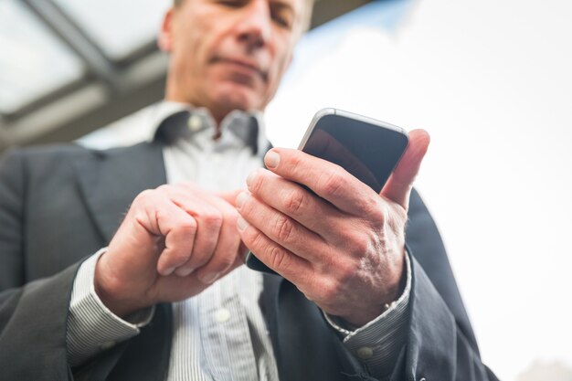 Zakenman die en op zijn slimme telefoon kijkt typt