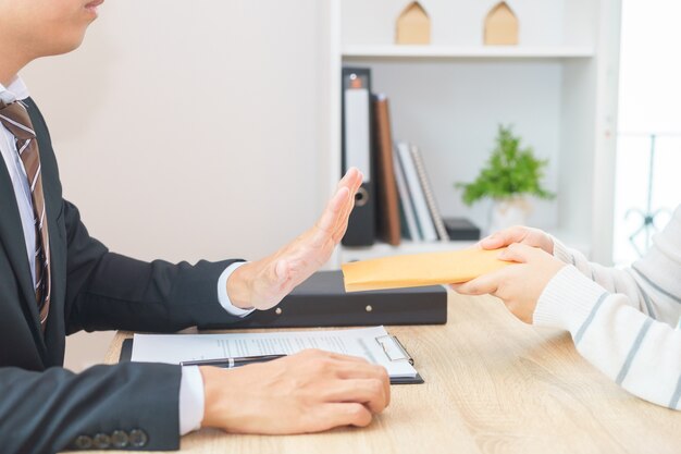 Zakenman die geld in envelop verwerpen die door een vrouw wordt aangeboden