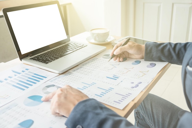 zakenman die grafieken analyseert en een laptop op zijn bureau gebruikt