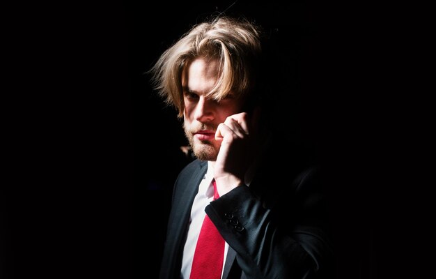 Zakenman die in het donker belt Man houdt een smartphone vast Portret van een zakenman op een donkere achtergrond