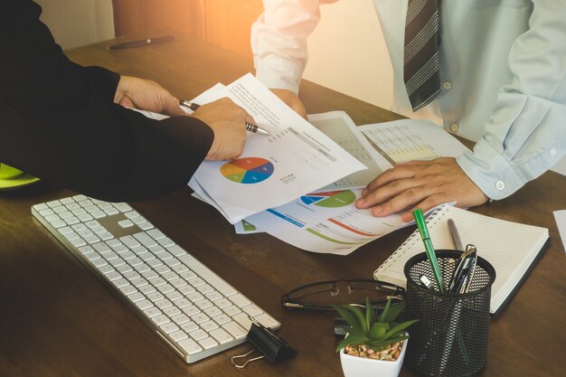 Zakenman die investeringsgrafieken met laptop computer op bureaulijst analyseren.