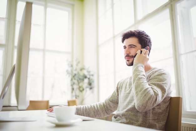 Zakenman die mobiele telefoon in bureau met behulp van