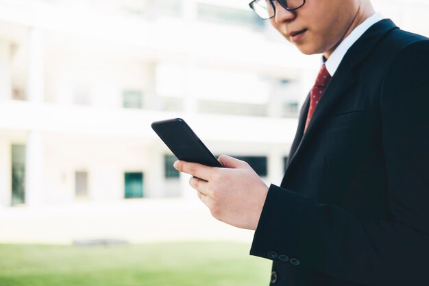 Zakenman die mobilofoonapp texting buiten bureau gebruiken.