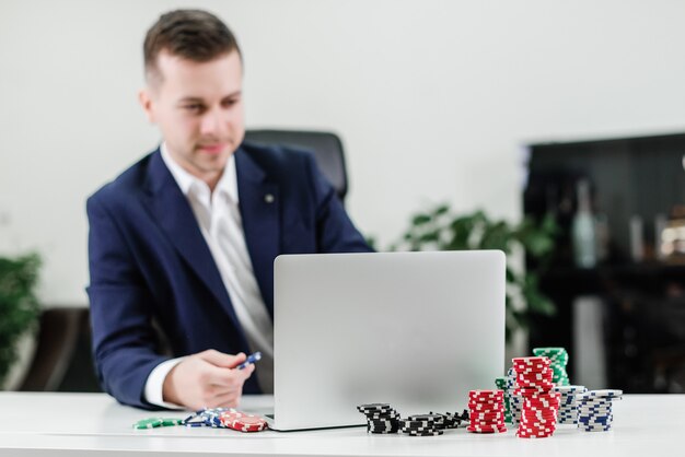 Zakenman die online casino en pook via laptop speelt