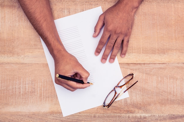 Zakenman die op papier bij bureau in bureau schrijft