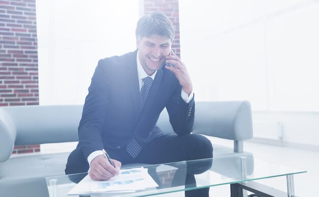 Zakenman die op smartphone in bureau spreekt