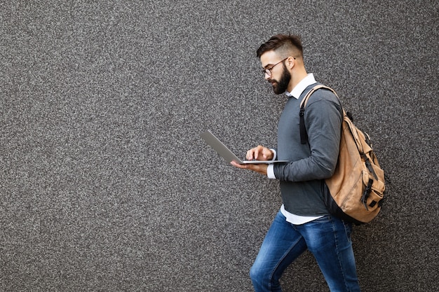 Zakenman die op straat loopt en zijn laptop vasthoudt, buiten aan het werk