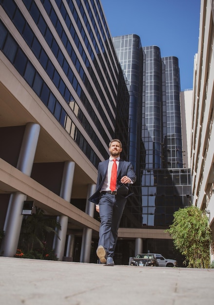 Zakenman die op straat loopt Zakenman loopt in de buurt van modern zakencentrum Bedrijfs- en architectuurconcept Zakelijk succes stap boost persoonlijke carrière en winnen