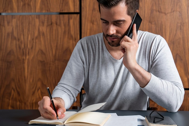 Zakenman die op telefoon spreekt en nota's neemt