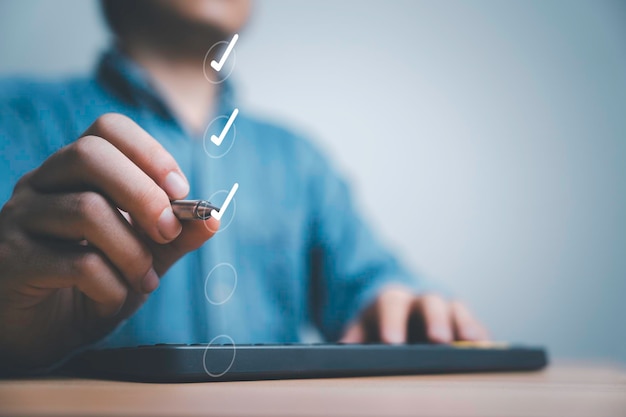 Foto zakenman die pen gebruikt, vink het juiste teken aan op het selectievakje voor de checklist voor kwaliteitscontrole van documenten en het zakelijke projectconcept