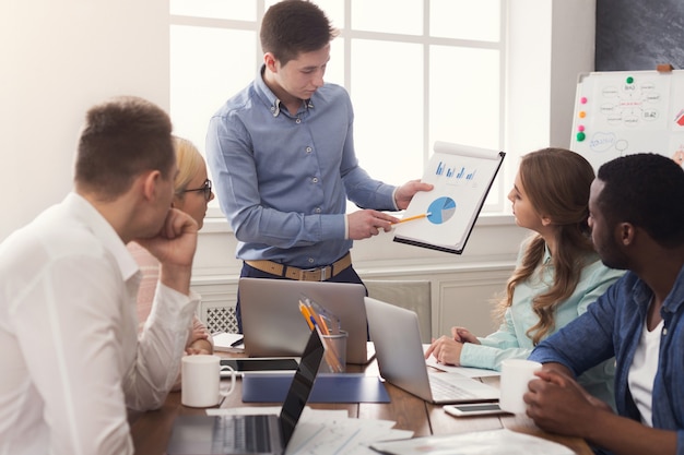 Zakenman die presentatie geeft aan collega's in moderne kantoren. Jong zakelijk team dat nieuwe marketingstrategie bespreekt, opstartproject plant, ruimte kopieert