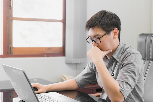 Zakenman die spanning met laptop computer heeft die in het bureau werkt