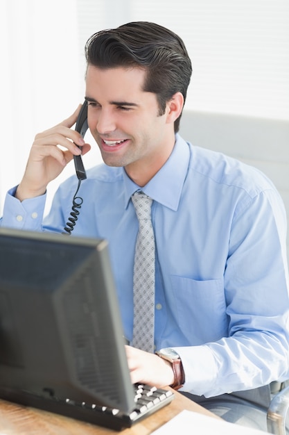 Zakenman die telefoongesprek hebben terwijl het gebruiken van zijn laptop