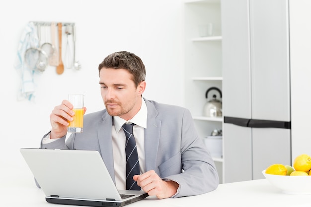 Zakenman die terwijl hij zijn laptop bekijkt drinken