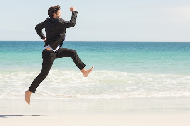 Zakenman die voor het overzees bij het strand springt